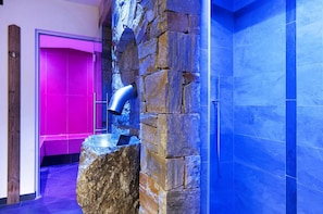 A stone wall with a water feature, a wooden door, and a blue-tiled wall.