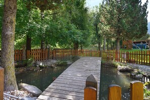 A wooden bridge over a calm water body, surrounded by trees and a wooden fence. - Room 'Olympia Zimmer 204' with Mountain View, Shared Garden and Wi-Fi (Sarnthein)