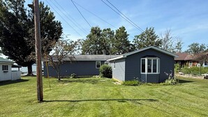 A single-story house with a small attached garage, a well-maintained lawn, and a utility pole with multiple wires. - Stunning fully remodeled 3 bedroom, 2 bath house directly on North Sandy Pond (Sandy Creek)