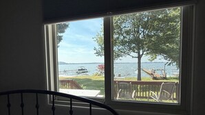 A bedroom with a window overlooking a deck and a lake. - Stunning fully remodeled 3 bedroom, 2 bath house directly on North Sandy Pond (Sandy Creek)