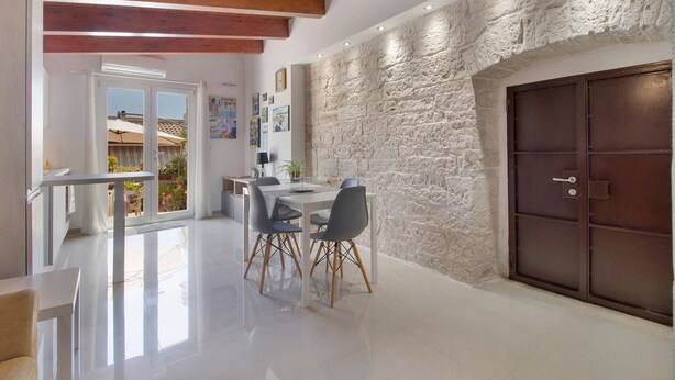 A dining area with a stone wall, a wooden ceiling, and a view of the outside. - Attica B&B – 'Red' Room with Shared Terrace, Wi-Fi, and Air Conditioning (Terlizzi)