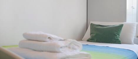 A hotel room with a bed, pillows, and folded towels.