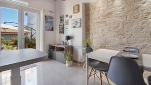 A modern dining area with a stone wall, a dining table, chairs, and potted plants. - Attica B&B – 'Red' Room with Shared Terrace, Wi-Fi, and Air Conditioning (Terlizzi)