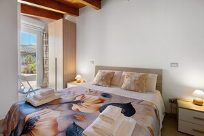 A bedroom with a bed, pillows, a nightstand, a lamp, and a view of the outside. - Attica BeB – 'Gialla' Room with Shared Terrace, Wi-Fi and Air Conditioning (Terlizzi)