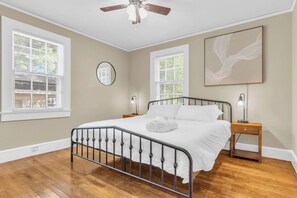 A bedroom with a bed, two bedside tables, a ceiling fan, and two windows with blinds. - Spacious Stay w 2 King Beds Minutes to Downtown (Greenville)