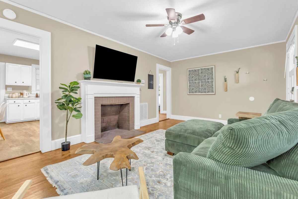 A living room with a fireplace, green sofa, and a ceiling fan.