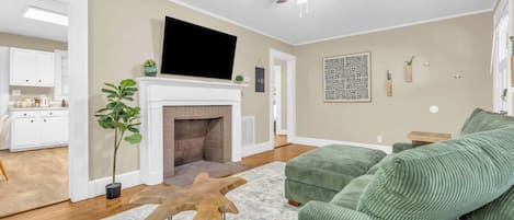 A living room with a fireplace, green sofa, and a ceiling fan.