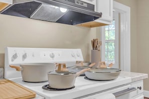 A kitchen with a white stove, pots, and a window with a view of greenery. - Spacious Stay w 2 King Beds Minutes to Downtown (Greenville)