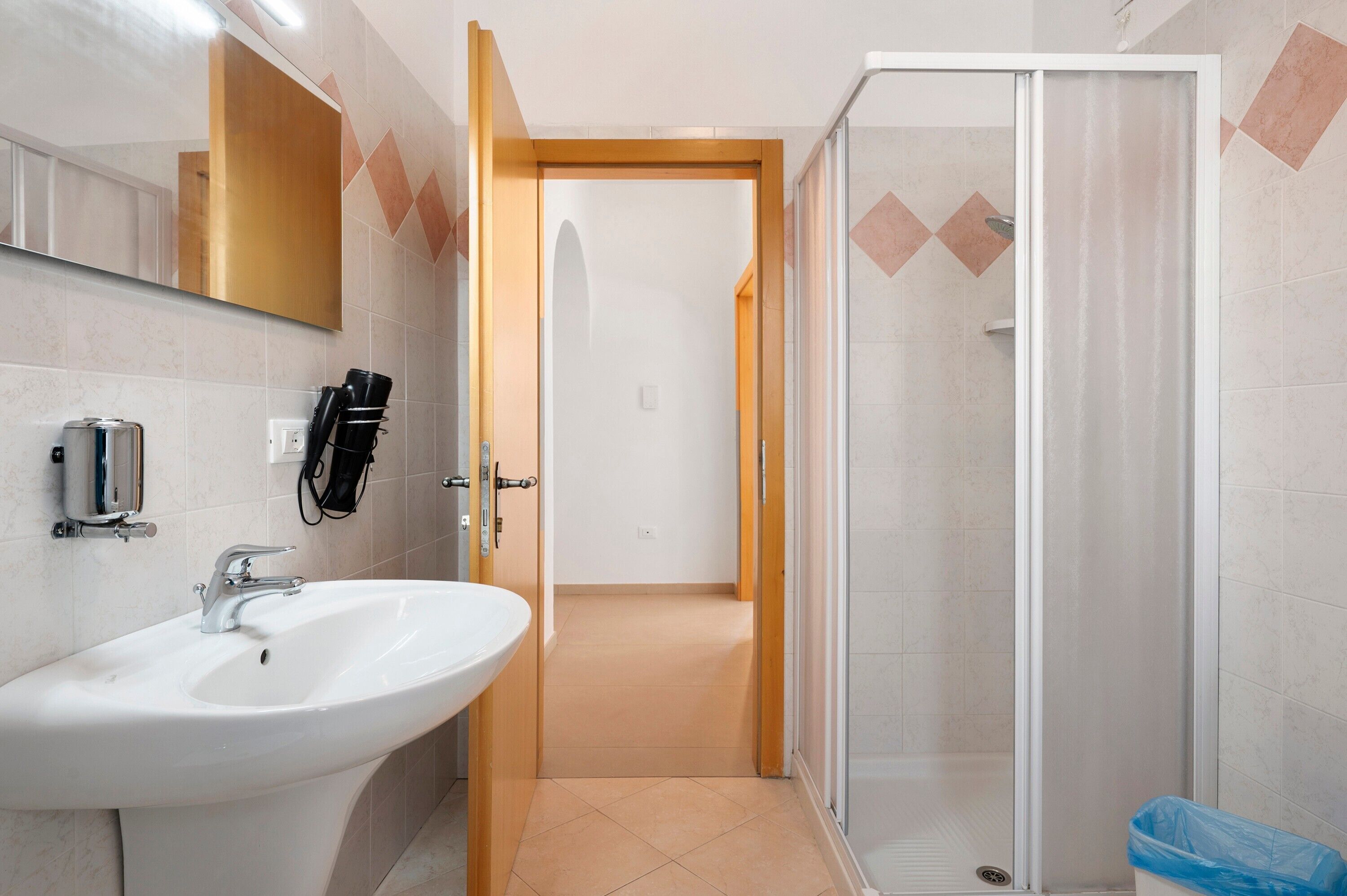 A bathroom with a sink, mirror, and shower.