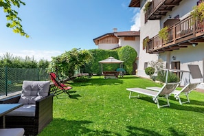A well-maintained garden with outdoor furniture, a pergola, and a building with balconies.