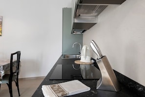 A modern kitchen with a black countertop, stainless steel appliances, a sink, and a chair.