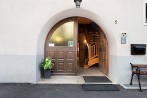 A hotel entrance with a wooden door, a staircase, a bench, and a mailbox.