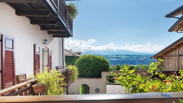 Un balcon avec vue sur les montagnes, une clôture en bois et un petit jardin.