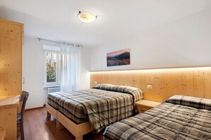 Ein Schlafzimmer mit zwei Betten, einem Holzkopfstück, einem Fenster mit Vorhängen, einer Heizung und einem Bild an der Wand.