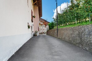 A narrow street with buildings on either side, a stone wall on the right, and a clear sky.