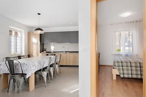 Une cuisine moderne avec des meubles de couleur grise, une table à manger avec des chaises et un luminaire suspendu.