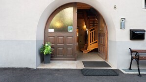 A hotel entrance with a wooden door, a staircase, a bench, and a mailbox. - Apartment 'La Canonica Pino' with Mountain View, Shared Garden and Wi-Fi (Brez)