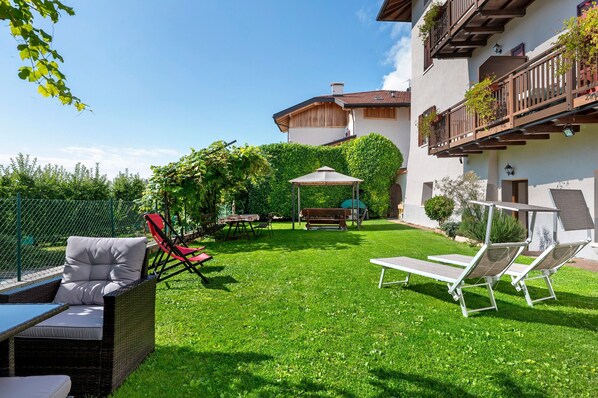 A well-maintained garden with outdoor furniture, a pergola, and a building with balconies.