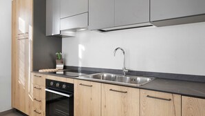 A modern kitchen with stainless steel appliances, wooden cabinets, and a black countertop. - Apartment 'La Canonica Pino' with Mountain View, Shared Garden and Wi-Fi (Brez)