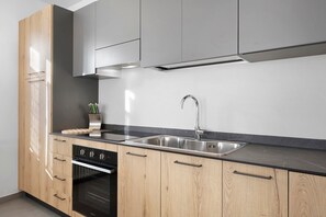 A modern kitchen with stainless steel appliances, wooden cabinets, and a black countertop.