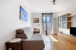 A modern living room with a sofa, a small table, a television, and a cabinet.