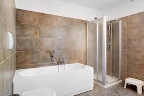 A modern bathroom with a bathtub, shower, and a small stool.