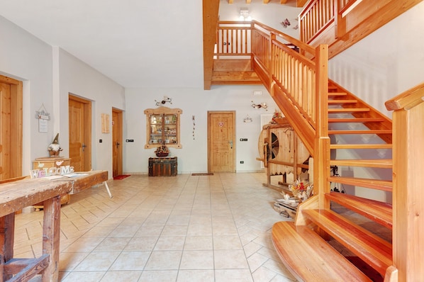 A spacious interior with a wooden staircase, a reception desk, and a tiled floor.