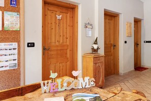 A reception area with a cork bulletin board, wooden doors, a welcome sign, and a gnome decoration.