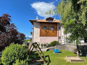 En toetages bygning med skråtag, trævinduesrammer og en lille balkon.
