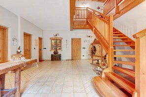 A spacious interior with a wooden staircase, a reception desk, and a tiled floor. - Apartment 'La Canonica Rosmarino' with Mountain View, Shared Garden and Wi-Fi (Brez)