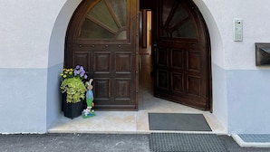 A building entrance with a large arched doorway, a small balcony above, and a mailbox on the wall.