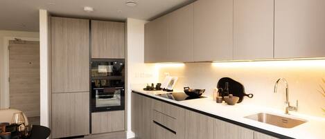 A modern kitchen with light wood cabinets, a black oven, and a white countertop.