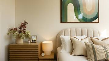 A bedroom with a bed, bedside table, lamp, and a framed picture.