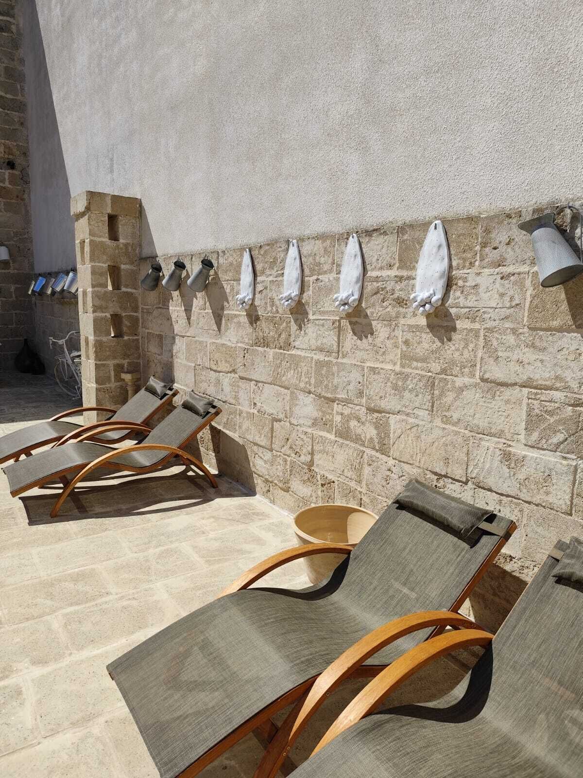 A sunlit outdoor seating area with stone walls and metal planters.