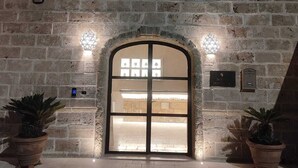 A stone building with a large arched entrance, potted plants, and a small window above the door. - King Suite with Private Jacuzzi - Charming in Felline | Borgo Don Ciccio (Felline)