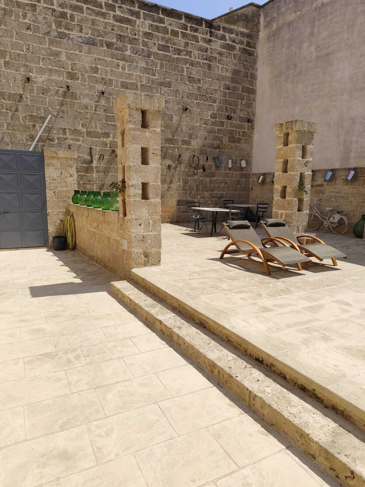 A courtyard with stone walls, a table, chairs, and a bicycle.
