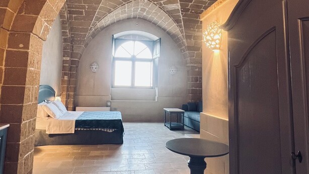 A room with a vaulted ceiling, a bed, a table, and a wardrobe. - King Suite with Private Jacuzzi - Charming in Felline | Borgo Don Ciccio (Felline)