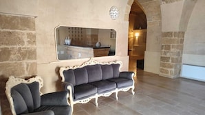 A living room with a stone wall, a mirror, a sofa, and a fireplace. - King Suite with Private Jacuzzi - Charming in Felline | Borgo Don Ciccio (Felline)