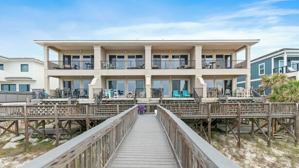 A beachfront property with a wooden boardwalk leading to a multi-story building with balconies. - Navarre Beachfront Townhome Southern Cross Sleeps 13 + Pet Friendly (Navarre)