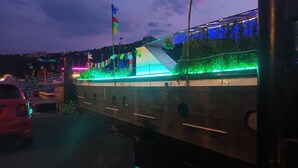 A waterfront building with a green-lit facade, a flag, and a dock area. - ATYPICAL COMFORT ROOM ON A BARGE ON THE RIVER SAONE (Lyon)