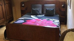 A bedroom with a large bed, a round window, wooden walls, and a painting on the wall. - ATYPICAL COMFORT ROOM ON A BARGE ON THE RIVER SAONE (Lyon)