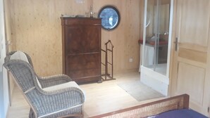 A room with a wooden floor, a wicker chair, a wooden cabinet, a ladder, and a door leading to a bathroom. - ATYPICAL COMFORT ROOM ON A BARGE ON THE RIVER SAONE (Lyon)