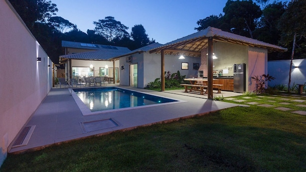 Une maison moderne dotée d’une piscine, d’un espace salon extérieur et d’un patio couvert.