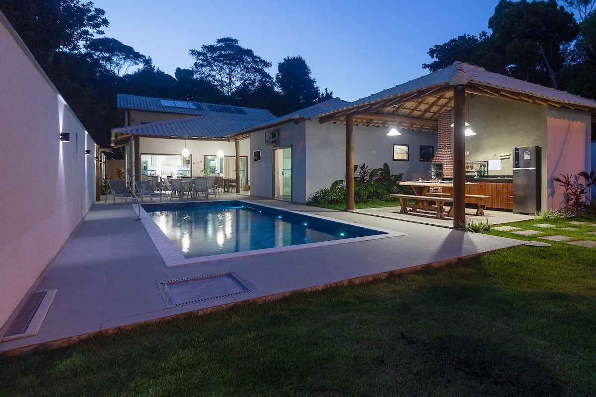 Una casa moderna con piscina, area salotto esterna e patio coperto.