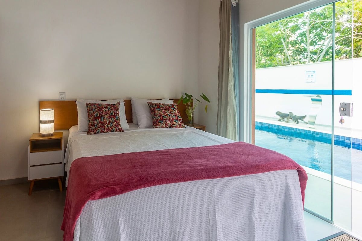 Una camera da letto con un letto, un comodino, un armadio in legno e vista su una piscina.