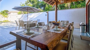 Un espace de restauration en plein air avec une table en bois prévue pour six personnes, entourée de chaises en osier.