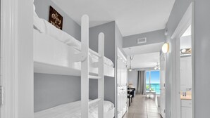 Une chambre d’hôtel avec des lits superposés, un bureau et vue sur la mer.