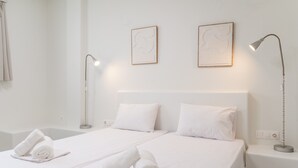 Een hotelkamer met een bed, twee bedlampjes en twee kunstwerken in lijsten aan de muur.
