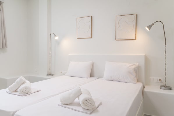 Una habitación de hotel con una cama, dos lámparas de noche y dos cuadros en la pared.