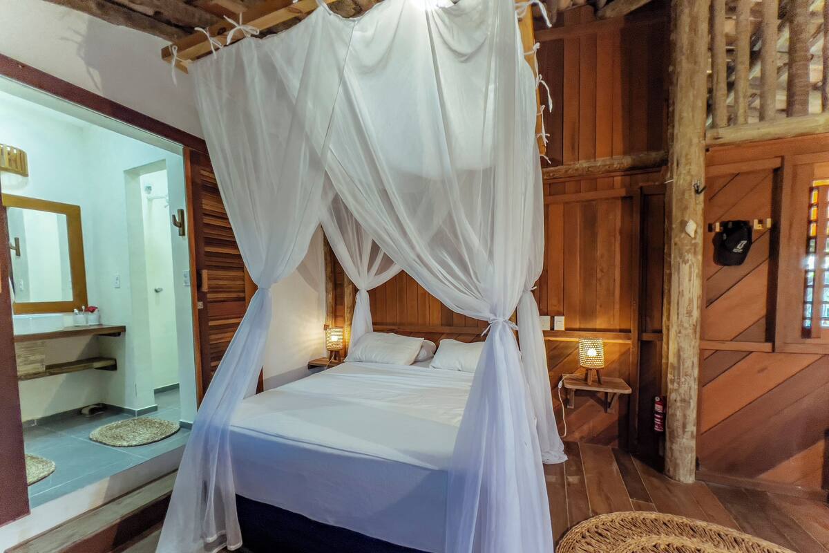 Un lit à baldaquin, des murs en bois, un miroir et des lampes de chevet.